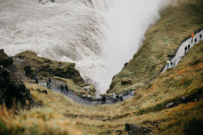 Tourist walking on mountain by waterfall