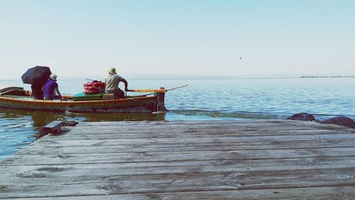 People sitting on pier at sea