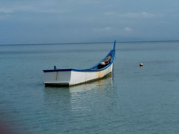 Boat moored in sea against sky