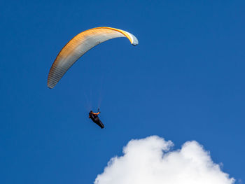 Low angle view of person paragliding against clear blue sky