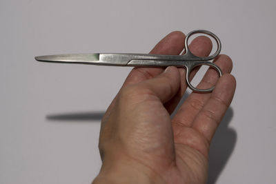 Close-up of hand holding metal against white background