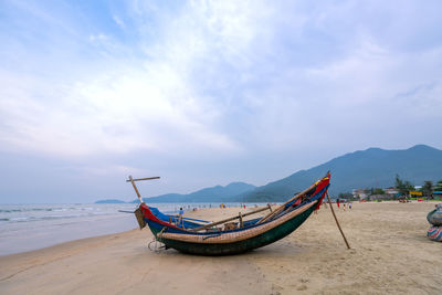 Fishing boat on beach against sky