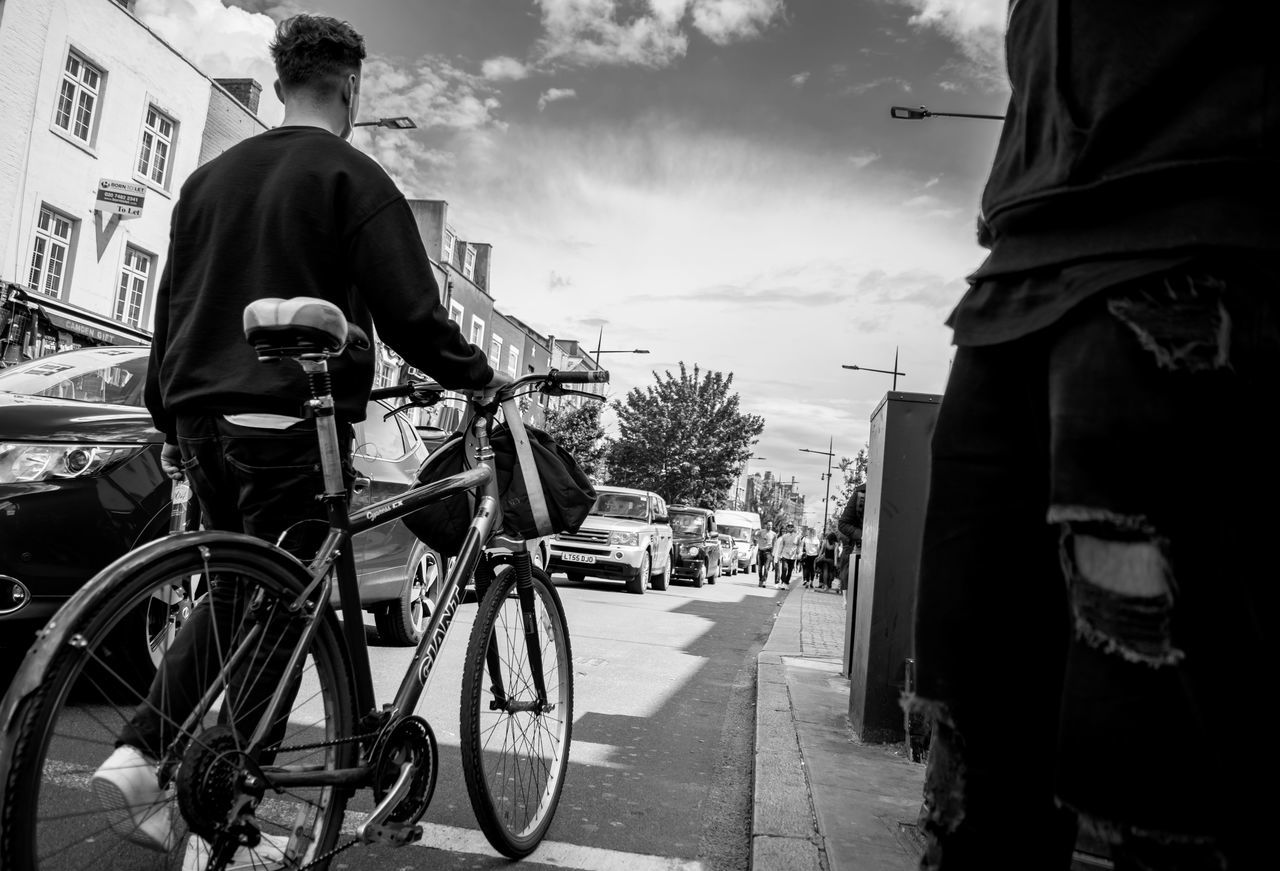 REAR VIEW OF MAN WITH BICYCLE ON STREET