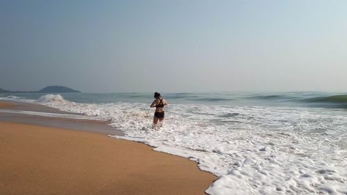 Full length of woman on beach against clear sky