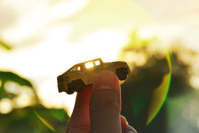 Cropped hand holding toy car in sunny day