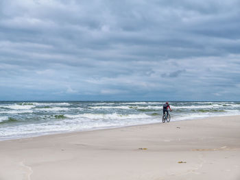 Biker biking along the sandy beach in slowinski national park, baltic sea, poland