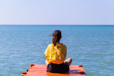 Rear view of woman looking at sea against clear sky