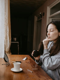 Portrait of young woman sitting on table at home