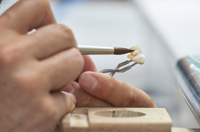 Close-up of dentist using paintbrush on artificial teeth