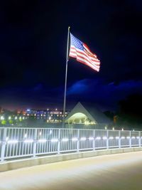 Light trails on illuminated city against sky at night