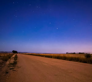 Road amidst field against sky at night