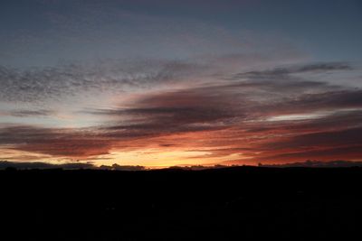 Silhouette landscape against dramatic sky during sunset