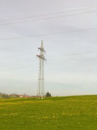 Low angle view of electricity pylon on field against sky