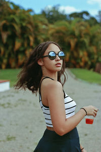 Side view portrait of teenage girl wearing sunglasses on field