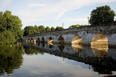 Arch bridge over river against sky