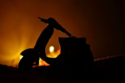 Close-up of silhouette toy motor scooter against sky during sunset