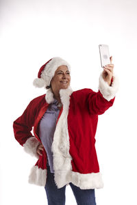 Young woman using phone while standing against white background