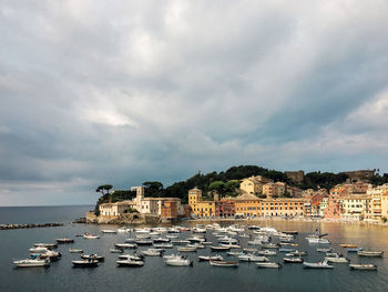 Sailboats moored in sea against buildings in city