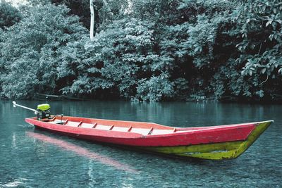 Red boat in river against trees