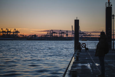 Silhouette woman by sea against clear sky during sunset