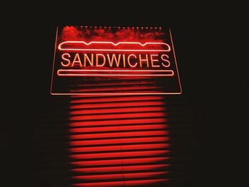 Low angle view of illuminated sign on wall at night