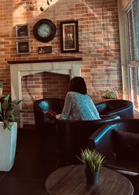 Rear view of woman sitting on table at home