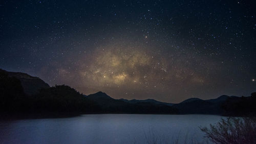 Scenic view of lake and mountains against sky at night