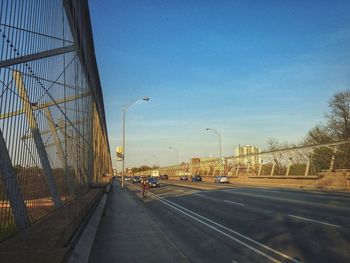 Road leading towards city against blue sky