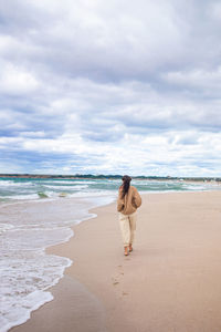 Rear view of woman on beach against sky