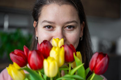 Close-up of young woman with red flowers