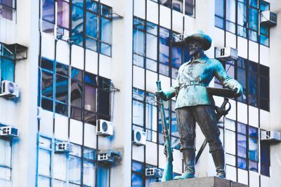 Low angle view of statue against modern building