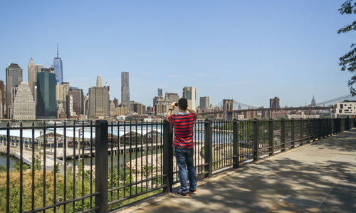 Rear view of man standing on railing in city