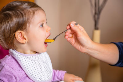 Cropped image of mother feeding baby girl