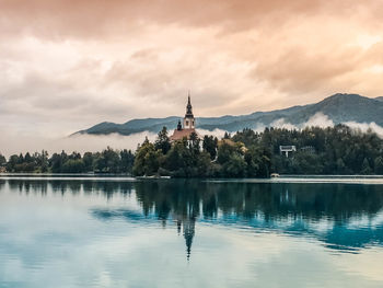 Scenic view of lake by church against sky