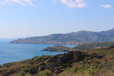 Scenic view of sea and mountains against blue sky