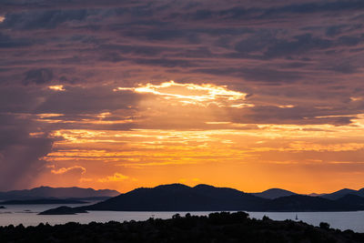 Scenic view of silhouette mountains against orange sky, murter, croatia