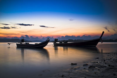 Boats moored in sea against sky during sunset