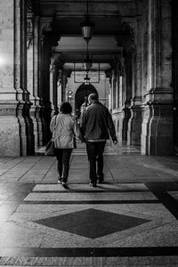 Rear view of people walking in corridor of temple