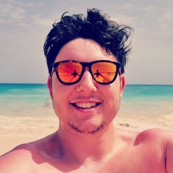 Portrait of young man wearing sunglasses at beach