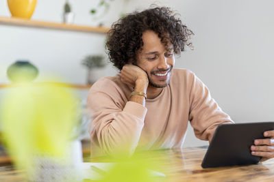 Young woman using phone while sitting on table