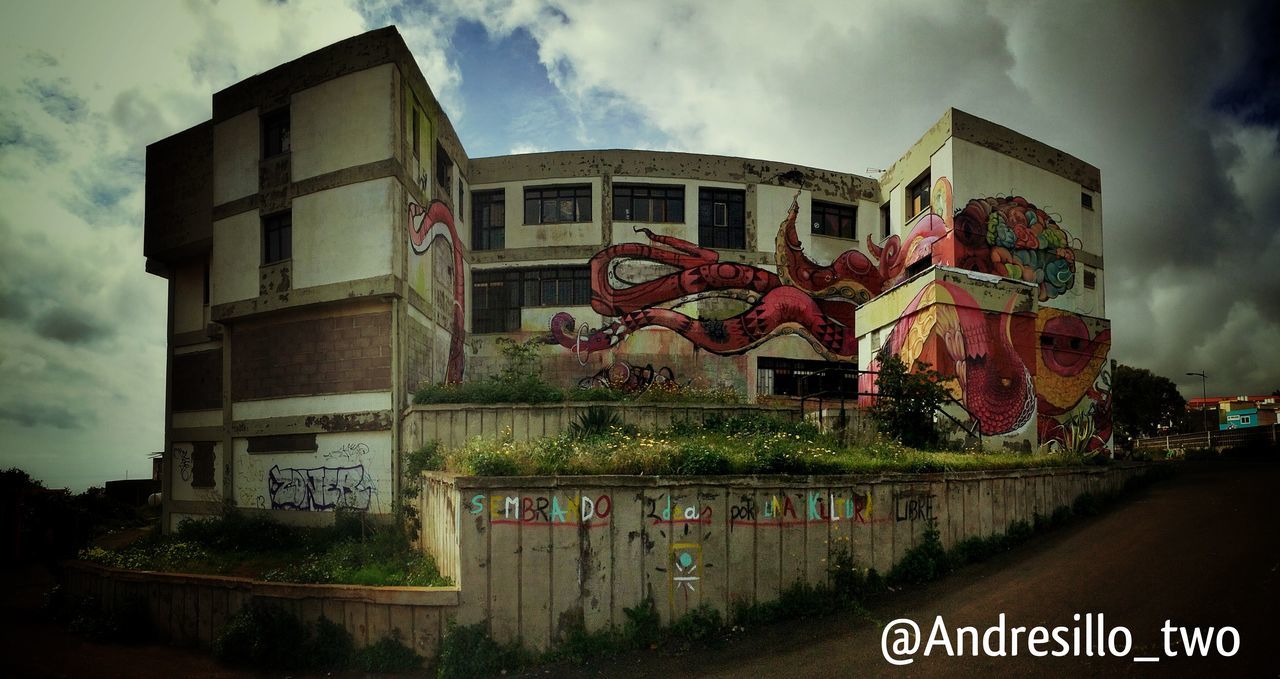 text, building exterior, architecture, western script, built structure, communication, sky, low angle view, cloud - sky, information sign, information, capital letter, non-western script, sign, cloudy, outdoors, day, road sign, graffiti, no people