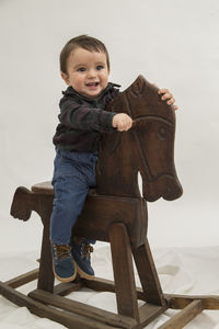 Portrait of happy boy sitting on wood against sky