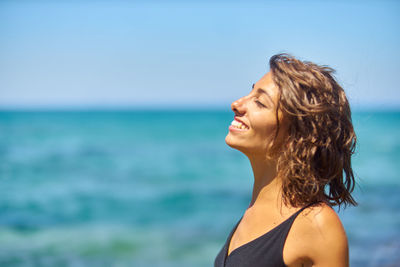 Close-up of smiling young woman against sea