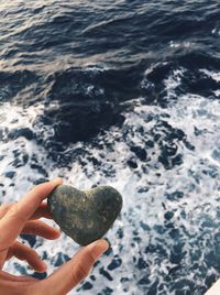 Midsection of person holding rock in sea