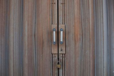 Close up the rusty folding gate door is locked tightly with a padlock