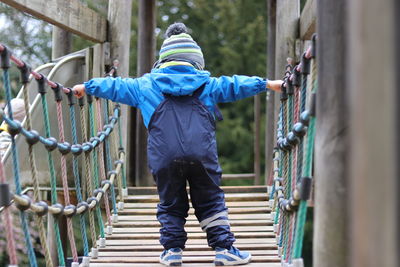 Rear view of boy standing on railing