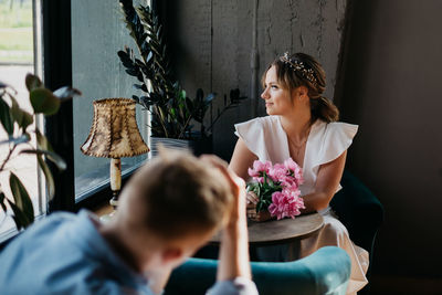 Woman holding flower bouquet against wall