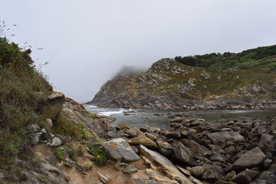 Scenic view of rocky mountains by sea against sky