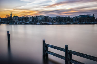 Illuminated buildings by river against sky in city amsterdam