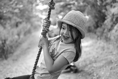 Cheerful girl swinging on rope at park